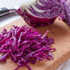 Red cabbage sliced on wood board, white wood background