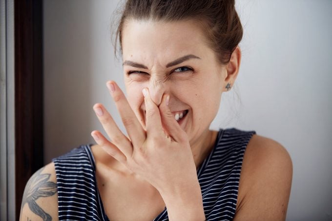 Headshot woman pinches nose with fingers hands looks with disgust something stinks bad smell situation.