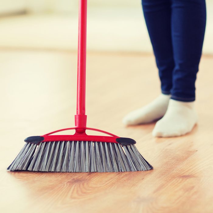 people, housework, cleaning and housekeeping concept - close up of woman legs with broom sweeping floor at home; Shutterstock ID 388206061