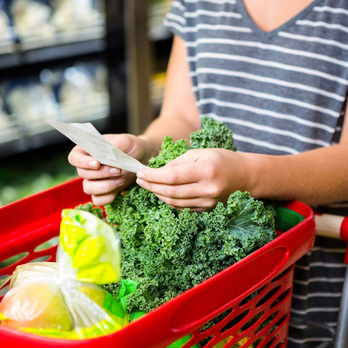 Woman with red basket holding list in supermarket; Shutterstock ID 398707321