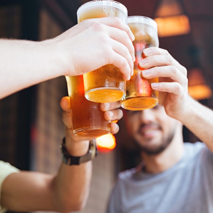 Happy male friends clinking with beer mugs in pub; Shutterstock ID 521300353