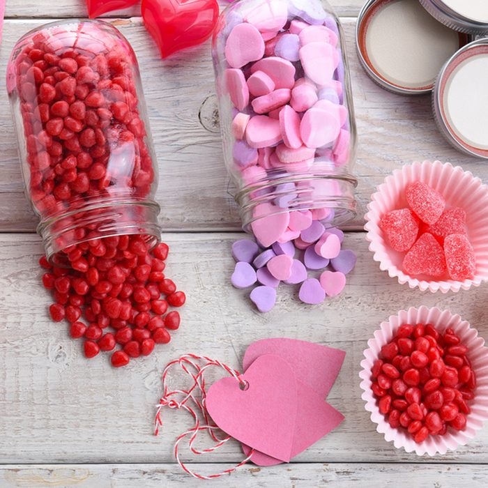 High angle view of different Valentines Day Candies on a rustic white wood table. Canning jars on their sides with candy spilling out.; Shutterstock ID 549418111