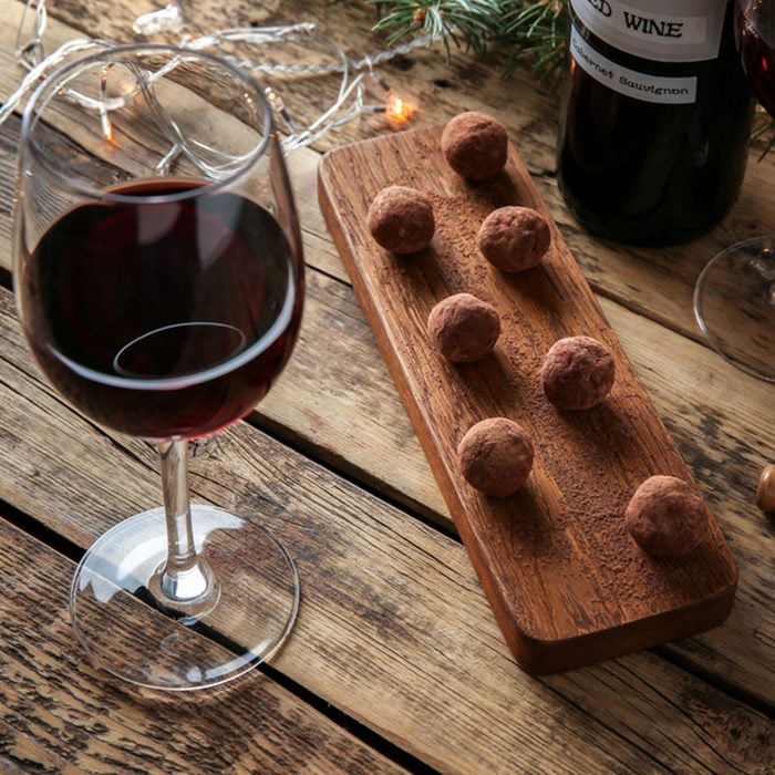 Red wine, chocolate dessert and Christmas decorations on wooden table; Shutterstock ID 600259550