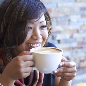 Portrait of beautiful Asian woman drinking cappuccino at a coffee shop.