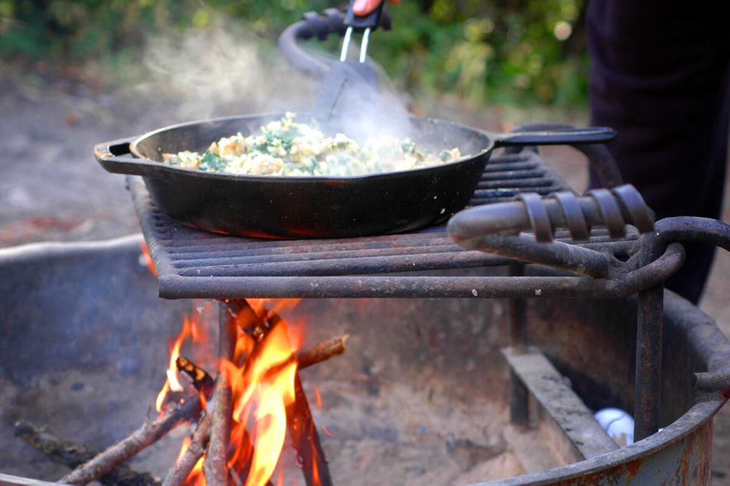 Cooking an egg scramble in a cast iron skillet over a campfire