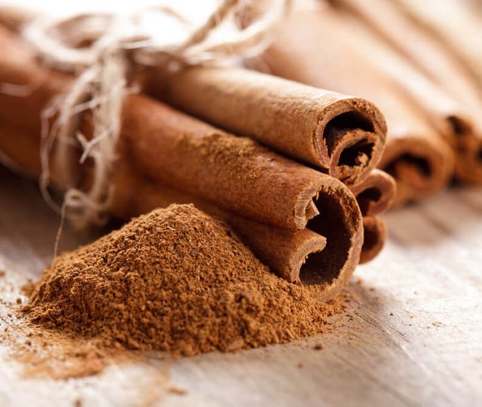 Cinnamon sticks and meal close up on wooden table