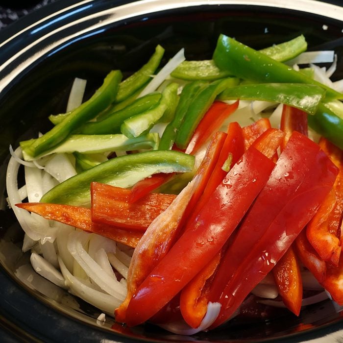 Sliced peppers visible inside of a red slow cooker