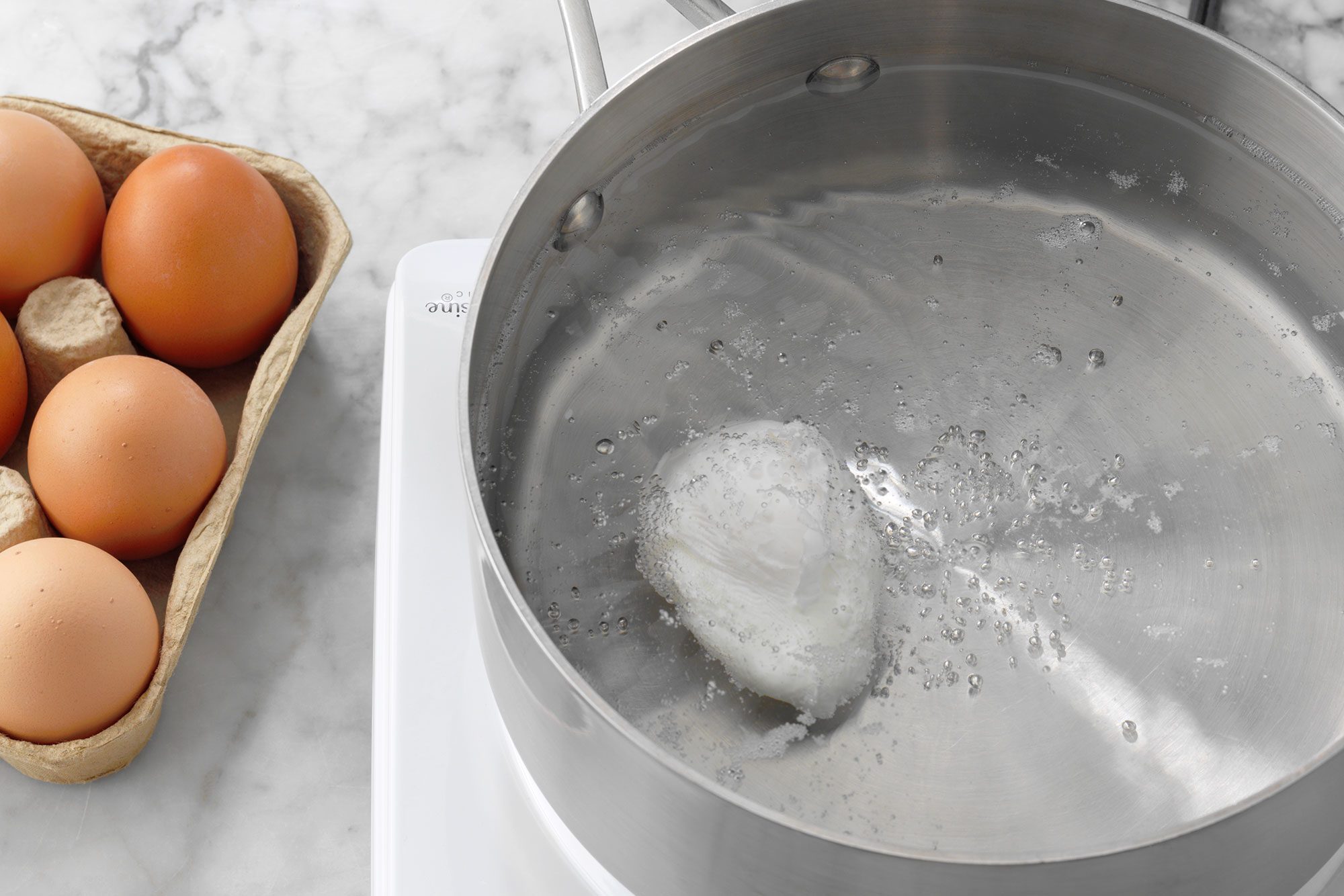 poached egg cooking in water in a pan on a hot plate