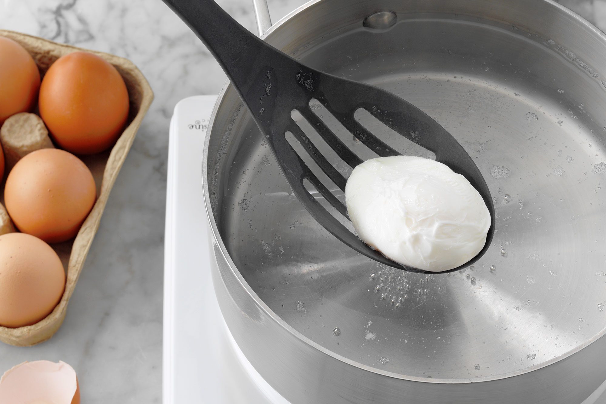 slotted spoon lifting poached egg from the water