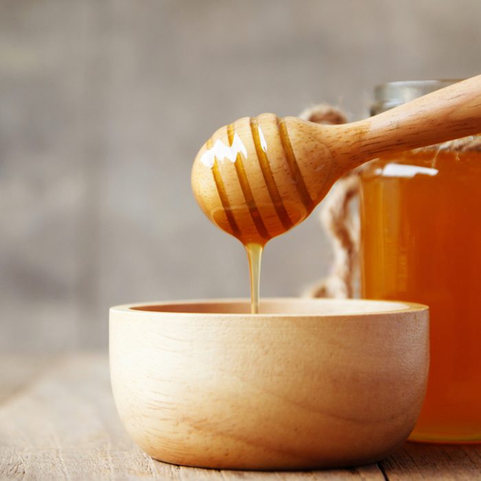 Honey being poured into wooden bowl