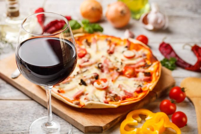 Glass of red wine with pizza on cutting board
