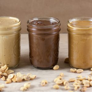 Peanut butter, hazlenut spread, and cashew butter on a wooden table