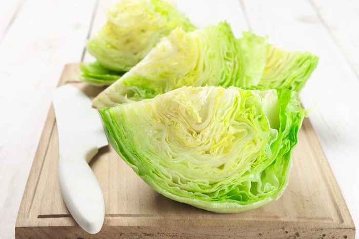 Cut pieces of iceberg lettuce with kitchen knife on cutting board