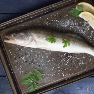 Fresh raw perch fish with spices,lemon and parsley on black background, top view