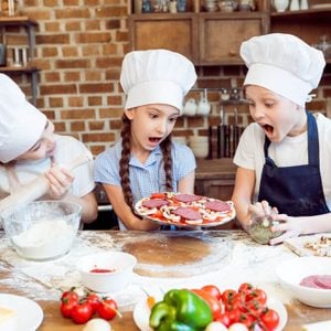 Kids cooking pizza in chefs hats