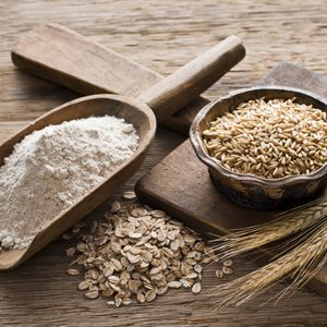 Whole grain and flour on wooden background close up