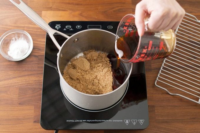 adding ingredients to a sauce pan on an electric burner plate