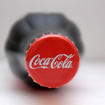 close up of coke bottle cap on bottle of coca cola laying on its side