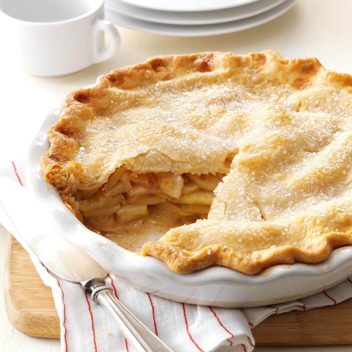 A close-up of a slice of apple pie, with a flaky crust and a gooey filling bursting with cinnamon and apples.