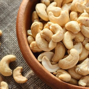 Raw cashews close-up in wooden bowl on sackcloth
