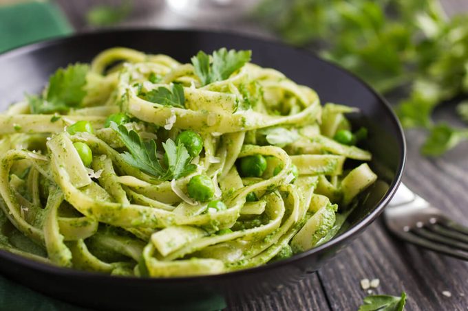 Tagliatelle pasta with spinach and green peas pesto, selective focus