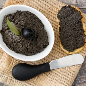 Black olive tapenade with anchovies, garlic and olive oil on wooden table