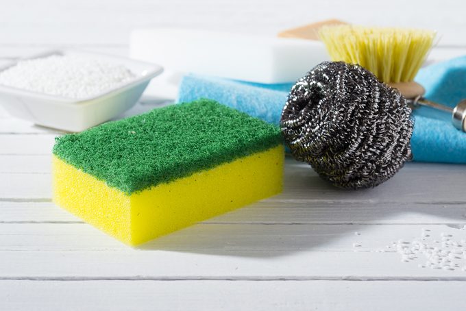 citric acid, cleaning brush, steel wool, sponges and bar of soap on white wooden table background