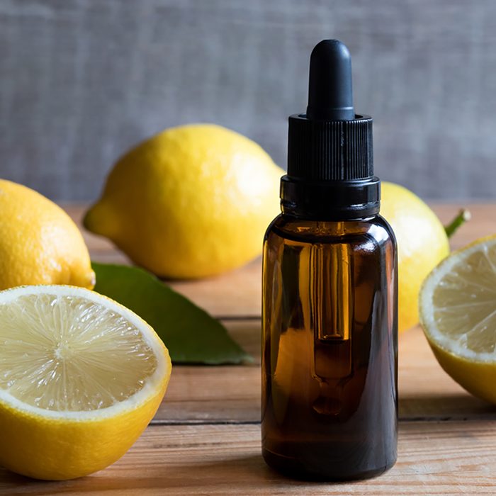 A bottle of lemon essential oil on a wooden table, with lemons in the background; Shutterstock ID 753261424; Job (TFH, TOH, RD, BNB, CWM, CM): Taste of Home