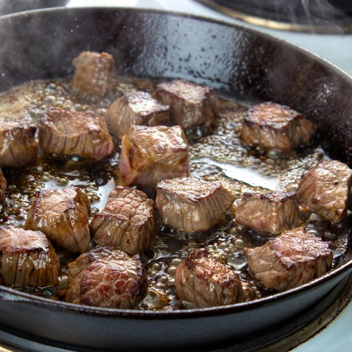 Frying beef bottom round roast cubes in cast iron skillet , meat flipped once; Shutterstock ID 476188450