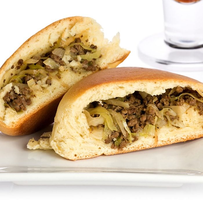 Single sliced bierock with seasoned ground beef, cabbage, and onion filling on a small plate