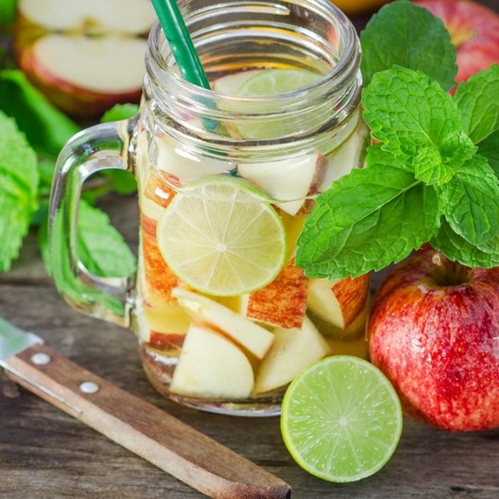 Mug delicious refreshing drink of apple fruits with mint on wooden, infused water