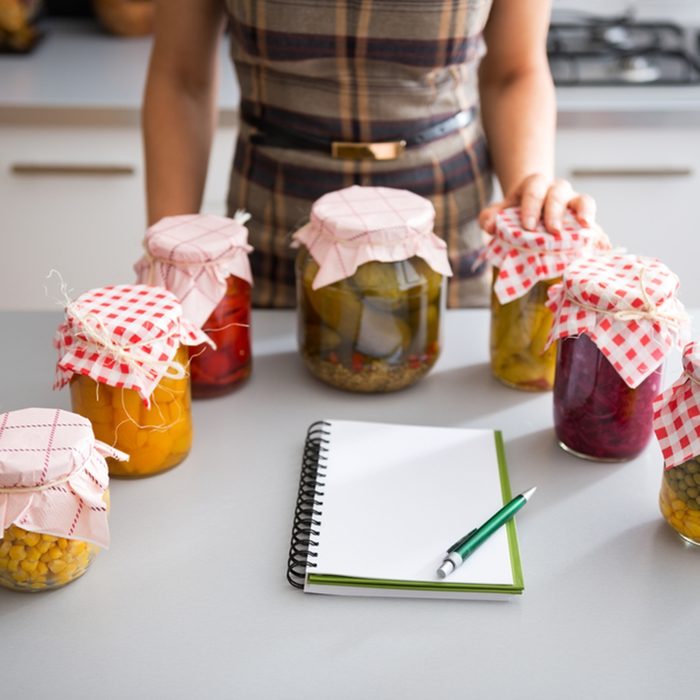 Closeup on notepad and young housewife with jars of pickled vegetables; Shutterstock ID 257211313; Job (TFH, TOH, RD, BNB, CWM, CM): Taste of Home