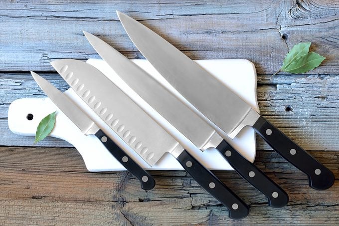 Set of kitchen knives on a board, top view.