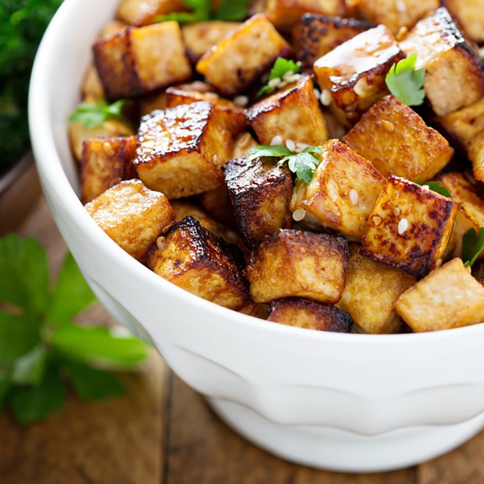 Stir fried tofu in a bowl with sesame and greens.