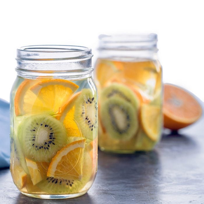 Infused water with kiwi and orange in jars, partly isolated