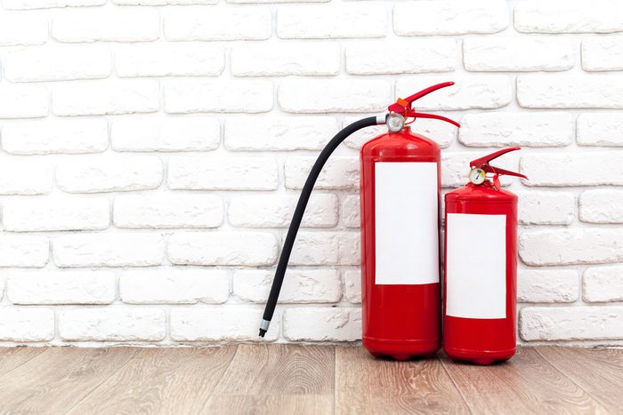 Fire extinguisher near white wall, ready for use