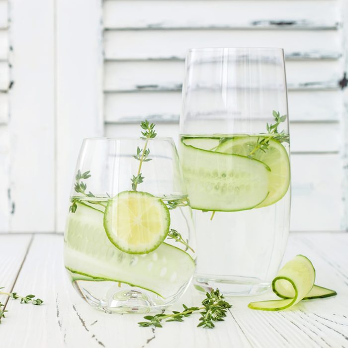 Cucumber infused hydrating water with thyme and lime. Homemade flavored lemonade on rustic old wooden table