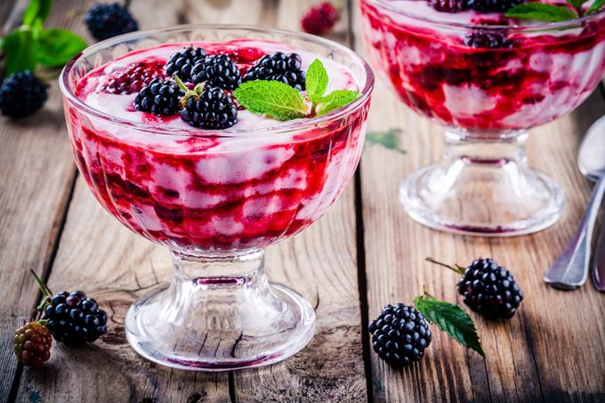 yogurt parfait with blackberry and mint in glass on rustic wooden table