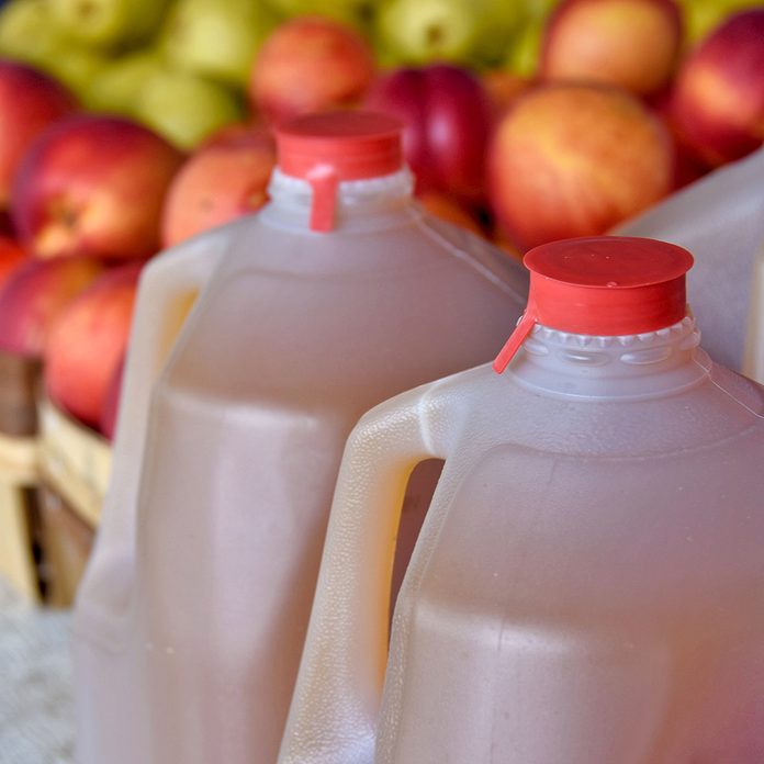 apple cider in plastic jugs with apples in produce boxes at the farmers market