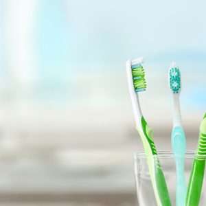 Toothbrushes in glass on blurred background.