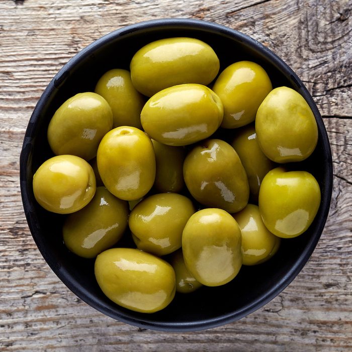 Bowl of pickled olives on wooden background