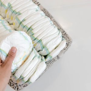 Stack of baby disposable diapers and Pacifier over white background.