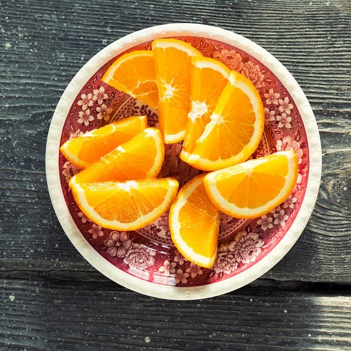 Slices of orange on a vintage plate, on wood. Shot from above.