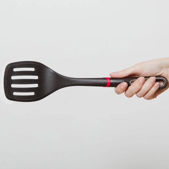 Close up of female hand horizontal holding black spatula isolated on white background. 