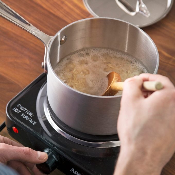 A person cooking rice on the stovetop.