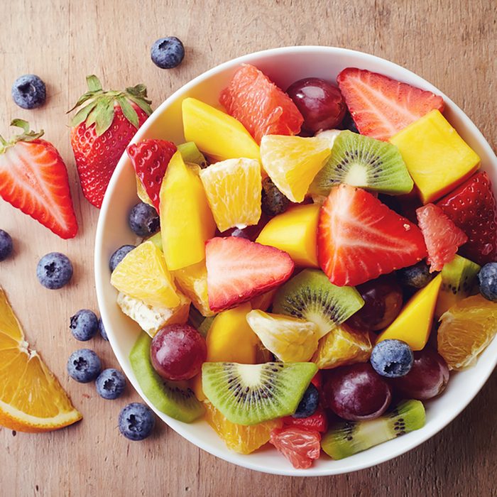 Bowl of healthy fresh fruit salad on wooden background