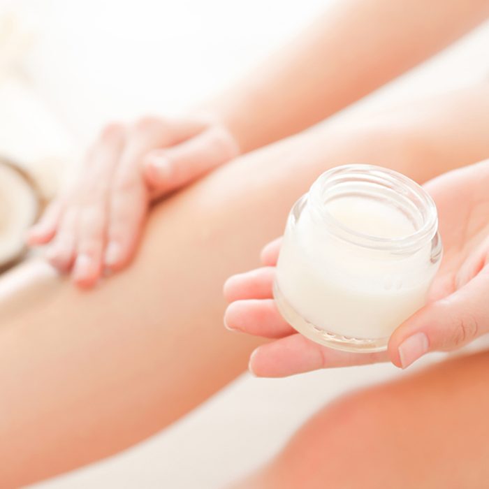 Woman applying coconut oil onto skin, closeup