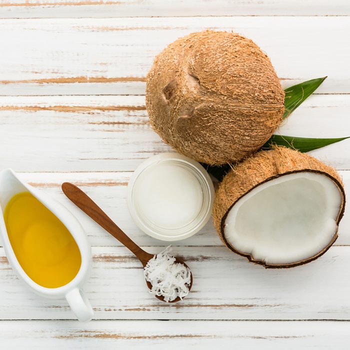 Coconut with coconut oil on white wooden table background. 