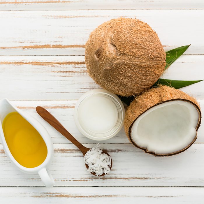 Coconut with coconut oil on white wooden table background.