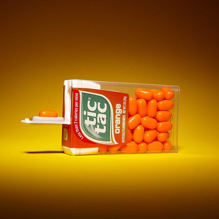 Tic tac container on its side with one candy held out in its lid